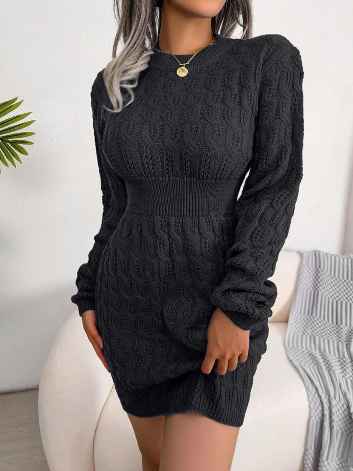 Person wearing a black cable knit dress with a white background