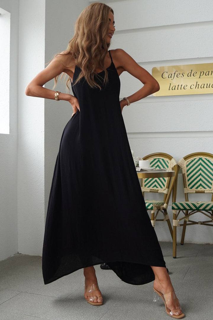 Woman in a black spaghetti strap maxi dress standing in a cafe setting