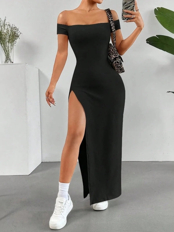 Woman wearing a black off-shoulder maxi dress with a high slit, standing indoors.