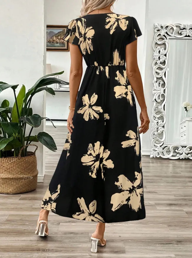 Woman wearing a black floral dress in a room with a plant and mirror.