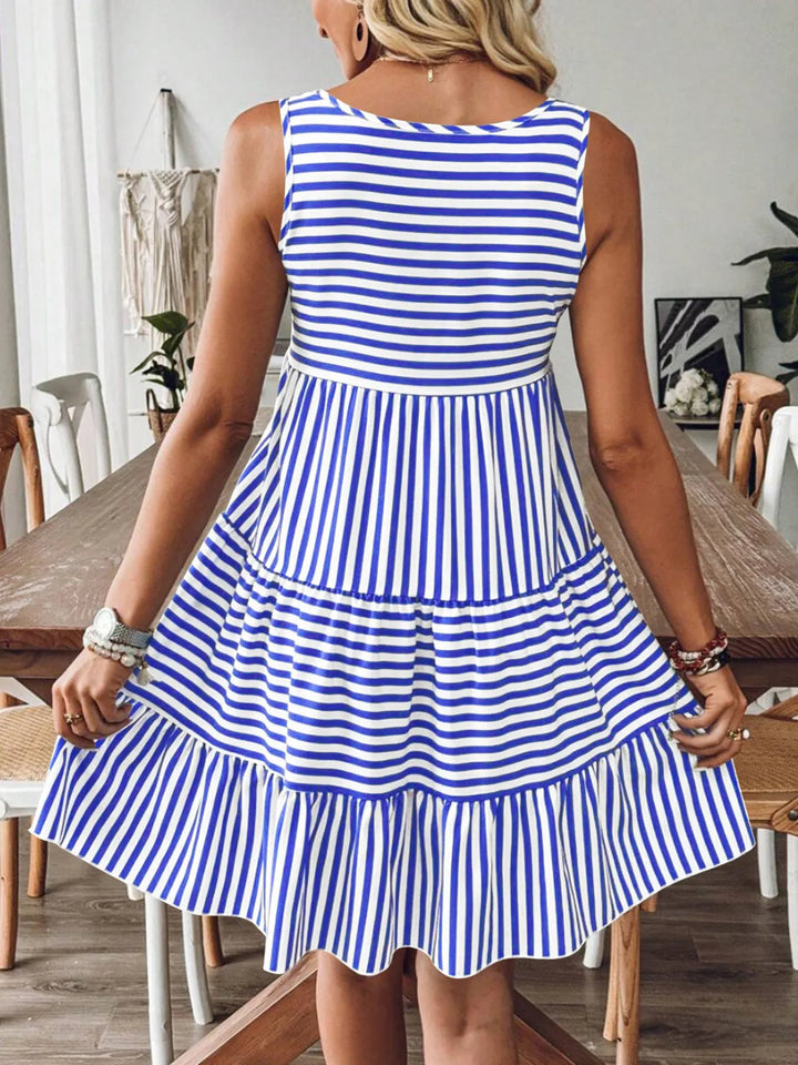 Woman wearing a blue and white casual striped dress in a room with wooden furniture.