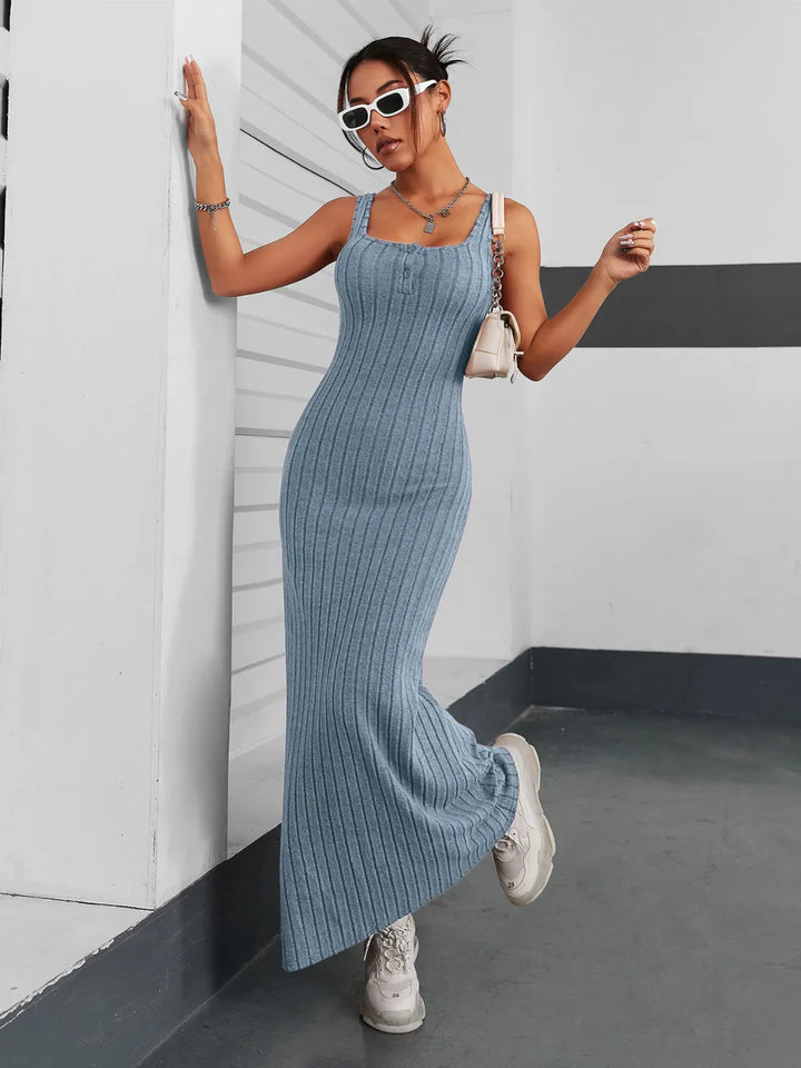 Woman in a french blue ribbed maxi dress standing against a white wall.