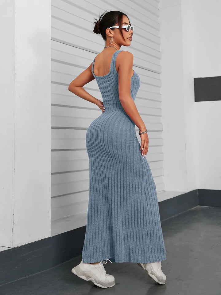 Woman wearing a french blue ribbed maxi dress against a white wall.