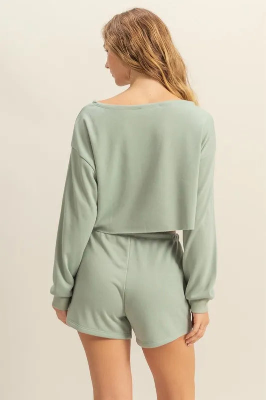Woman wearing a light green long-sleeve top and shorts set on a beige background