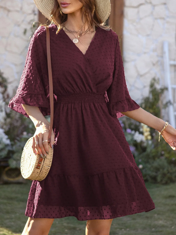 Woman wearing a burgundy dress with a straw bag in an outdoor setting