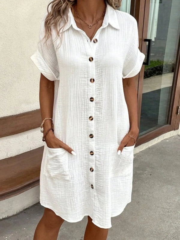Woman wearing a white casual  button-up dress standing outdoors.