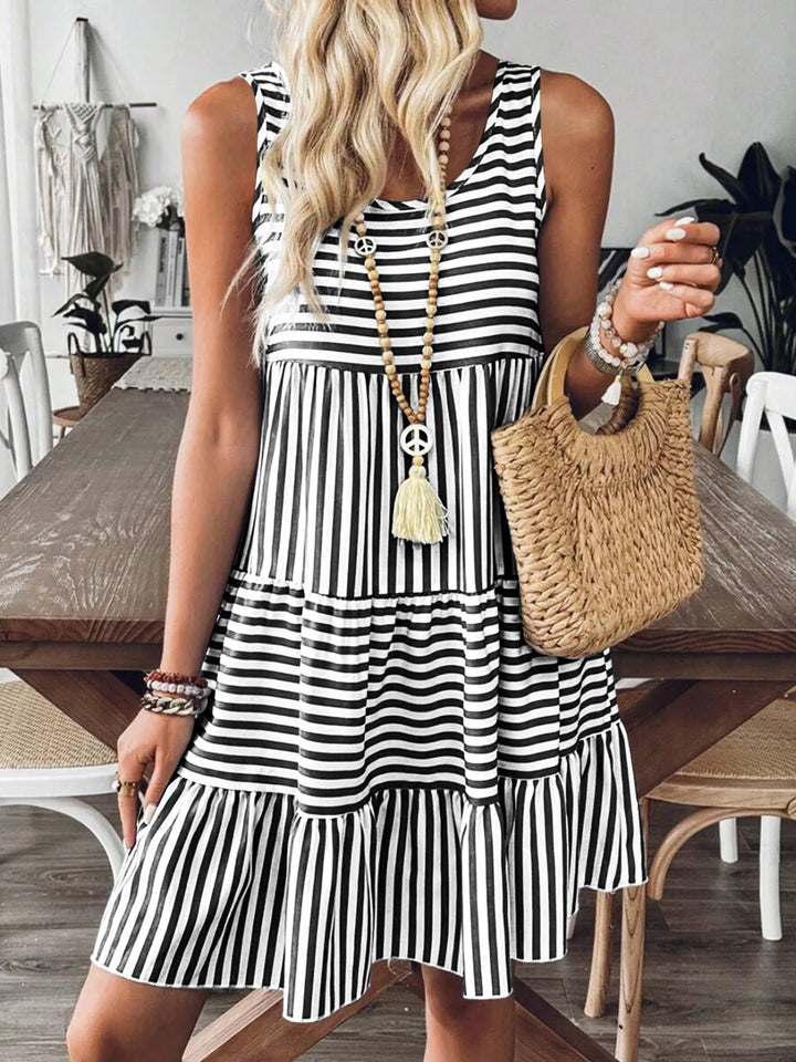 Woman wearing a black and white casual striped dress in a dining room setting.
