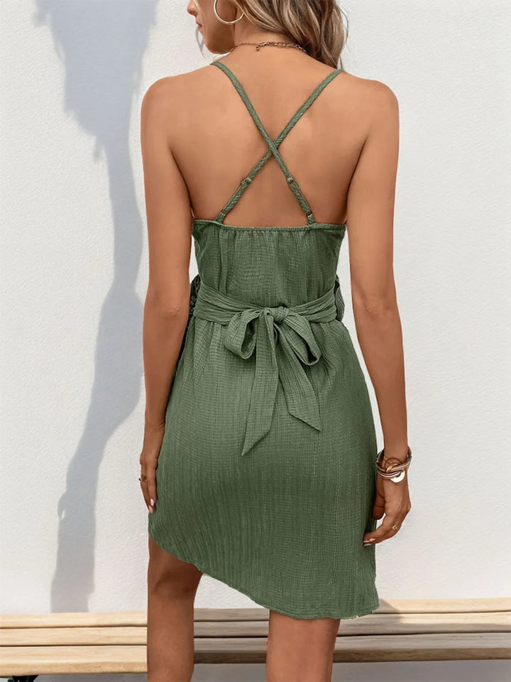 Green dress with criss-cross straps and tie waist worn by a person against a white background