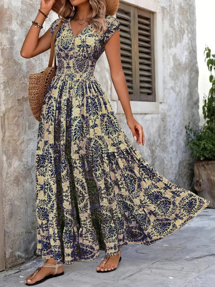 Woman wearing a dark blue floral dress standing against a stone wall.