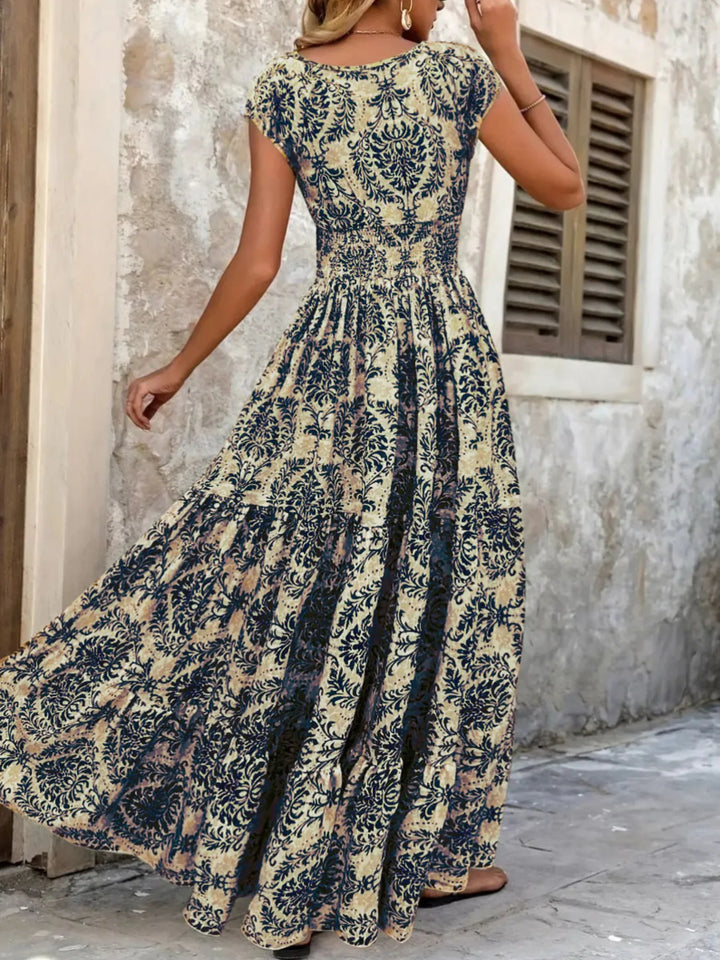 Woman wearing a dark blue maxi floral dress in front of a stone wall.
