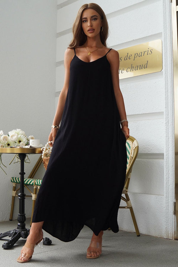 Woman wearing a black spaghetti strap maxi dress standing in an elegant interior setting.