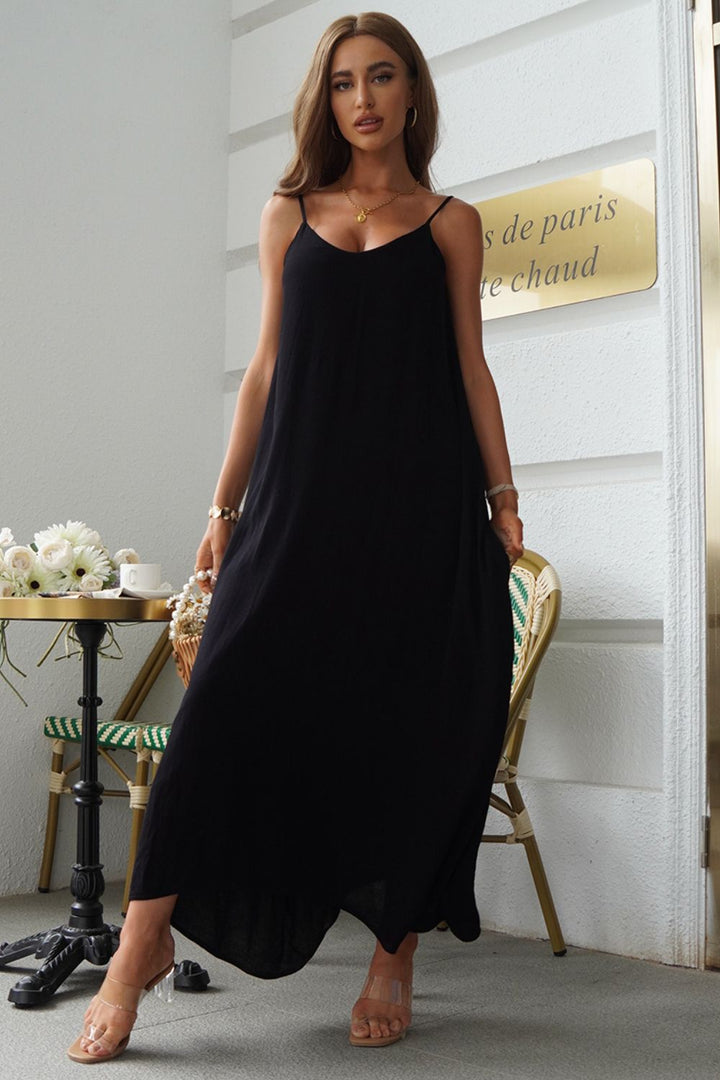 Woman wearing a black spaghetti strap maxi dress standing in an elegant interior setting.