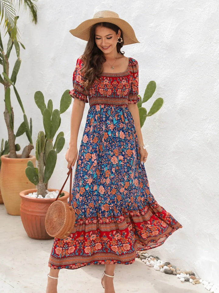 Woman in a colorful floral midi dress and wide-brimmed hat standing in front of cacti.