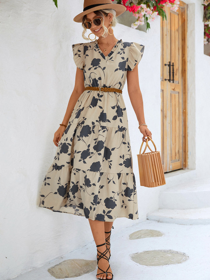 Woman wearing a floral dress with a white wall and wooden door in the background