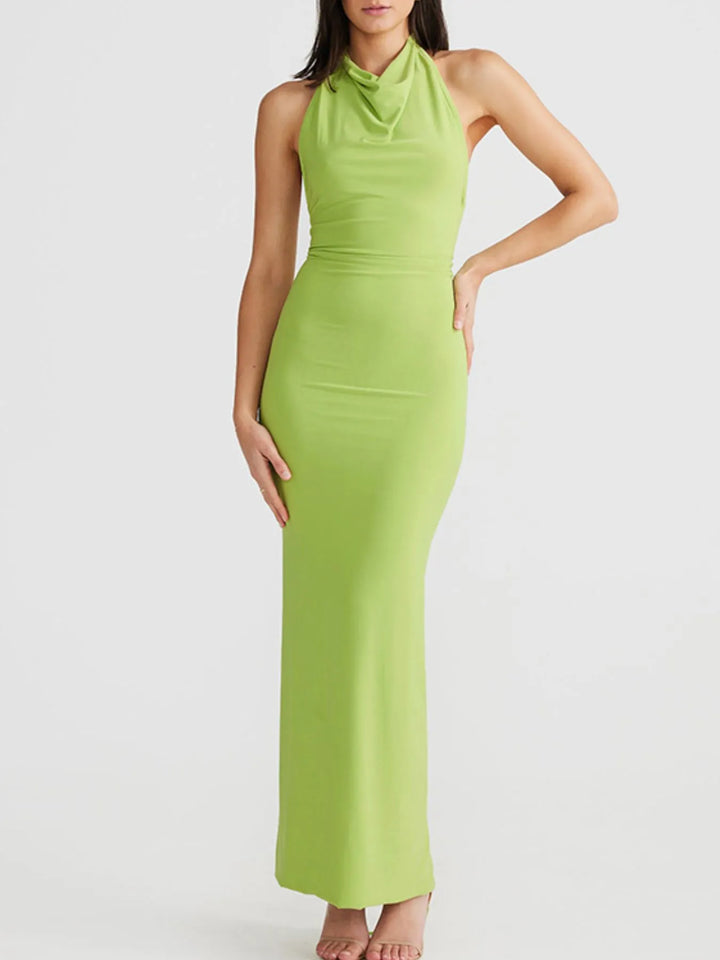 Woman wearing a green halter neck backless slit maxi dress on a white background