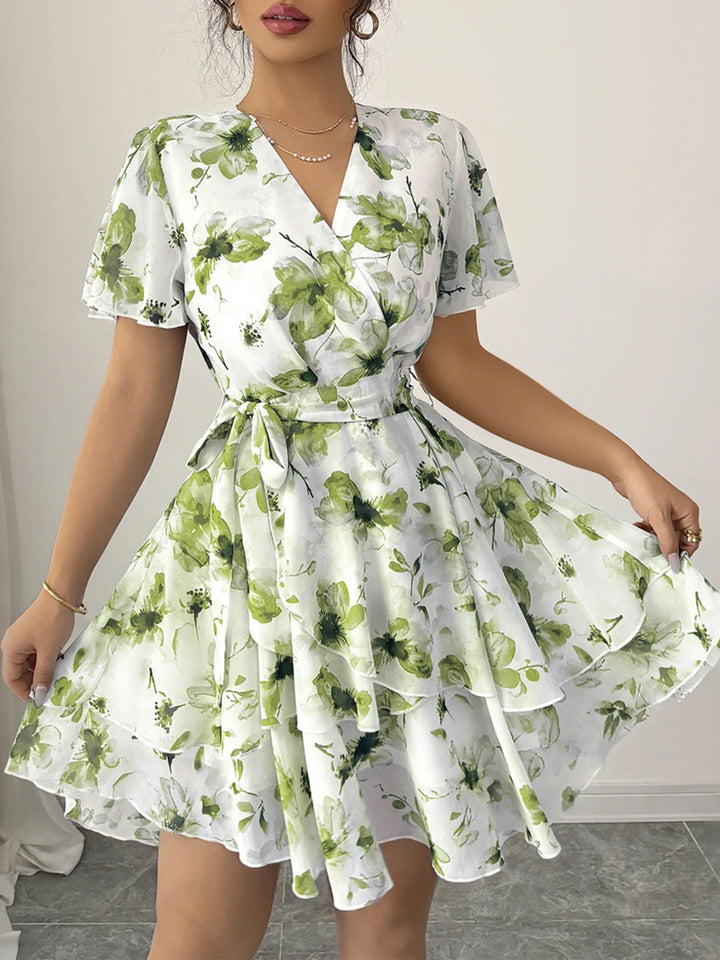 Woman wearing a white dress with green floral pattern indoors.