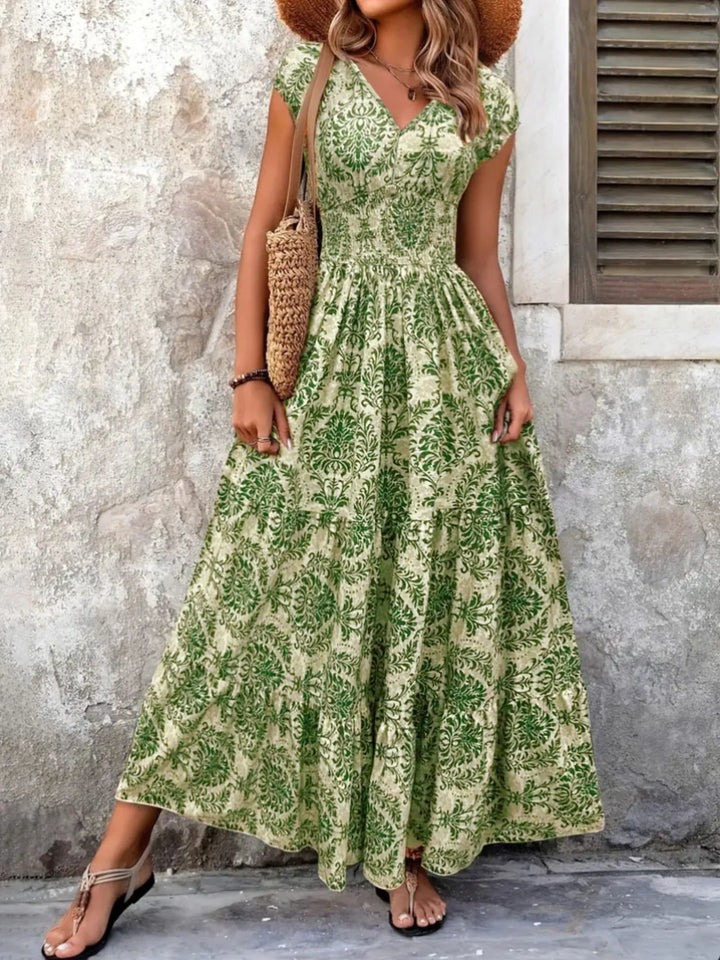 Woman wearing a green floral maxi dress against a textured wall.