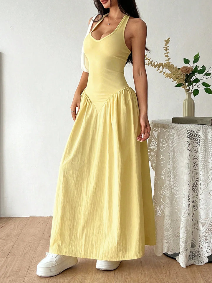 Woman wearing a yellow Halter Neck Maxi Dress standing indoors with a decorative plant in the background