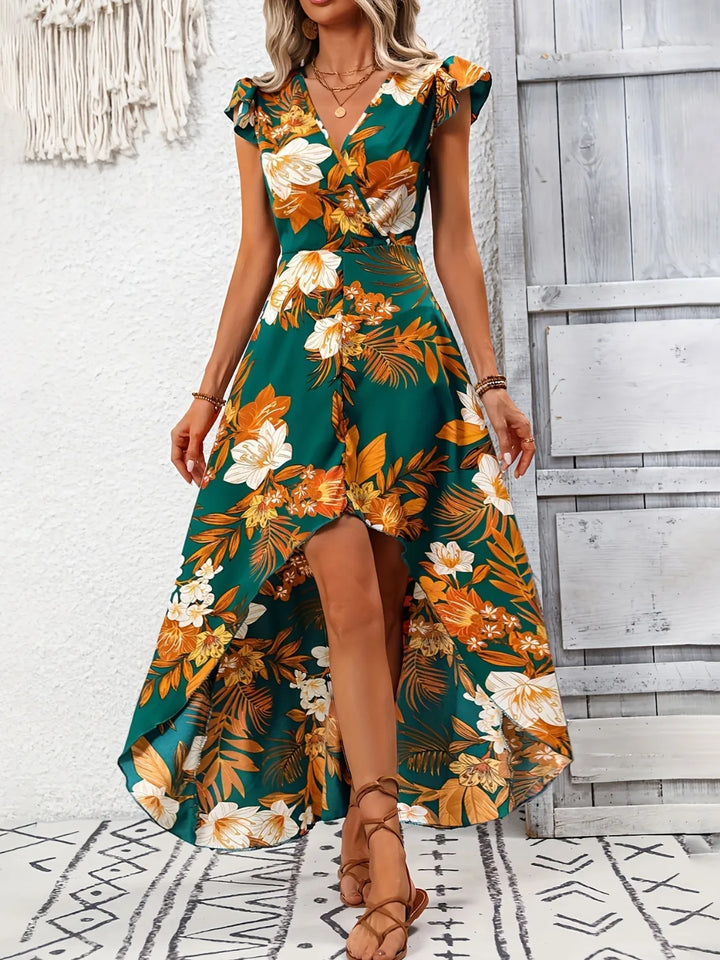 Woman wearing a floral maxi dress standing against a wooden wall.