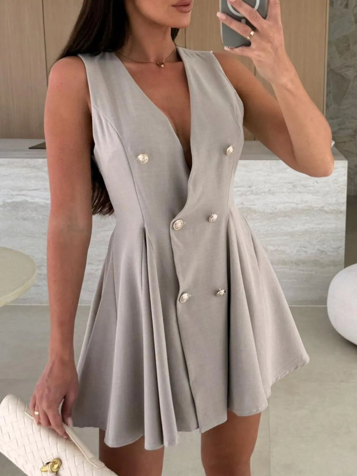 Woman wearing a gray dress with pearl buttons in an indoor setting