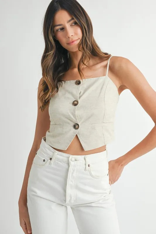 Woman wearing a white button-up top and white pants on a plain background