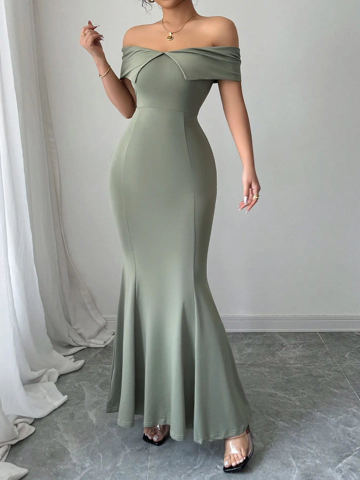 Woman wearing a sage off-shoulder evening gown in a minimalistic setting.