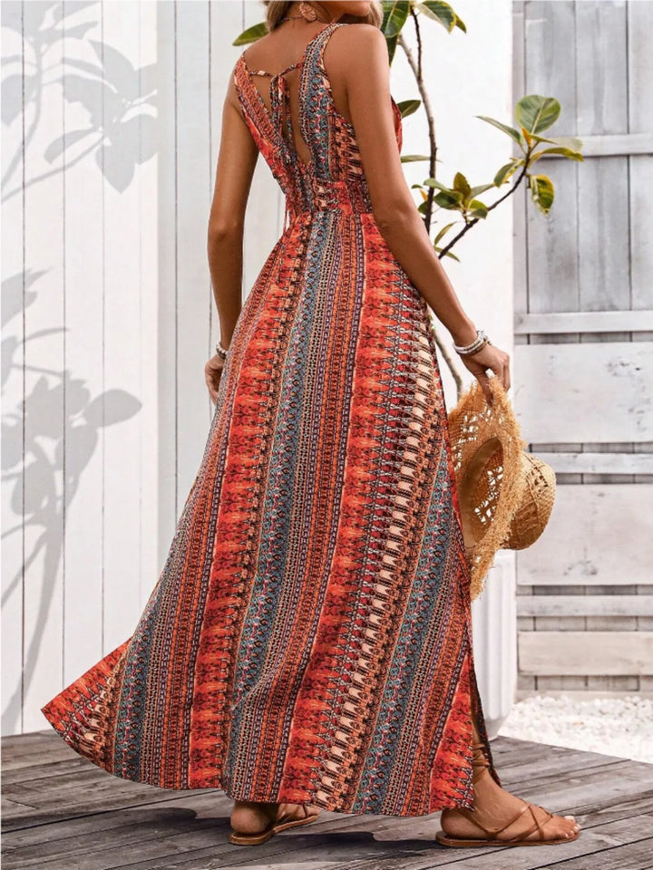 Woman in a patterned maxi dress holding a straw bag on a wooden deck.