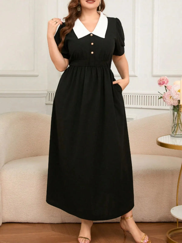 Person wearing a black dress in an indoor setting with a couch and flowers.