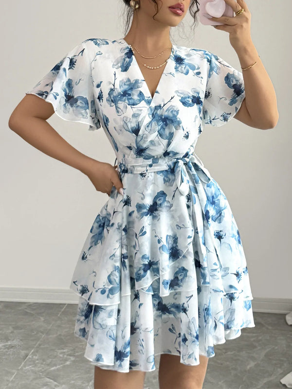 Woman wearing a blue and white floral dress against a plain background
