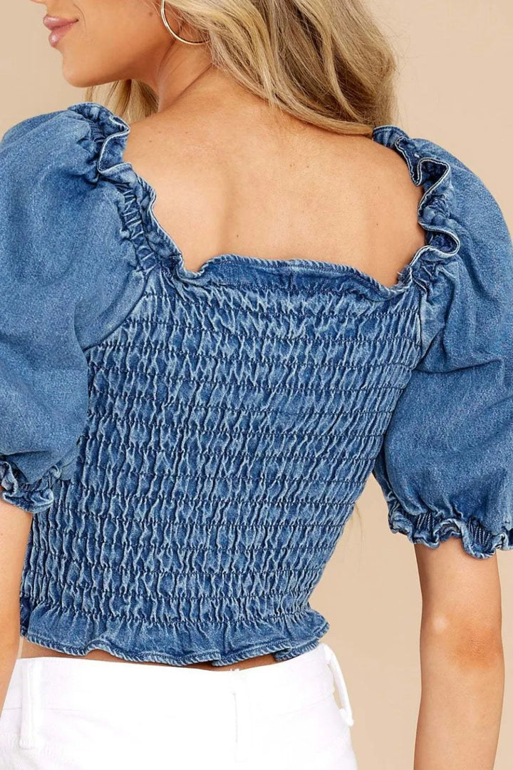 Blue denim top with puff sleeves on a beige background