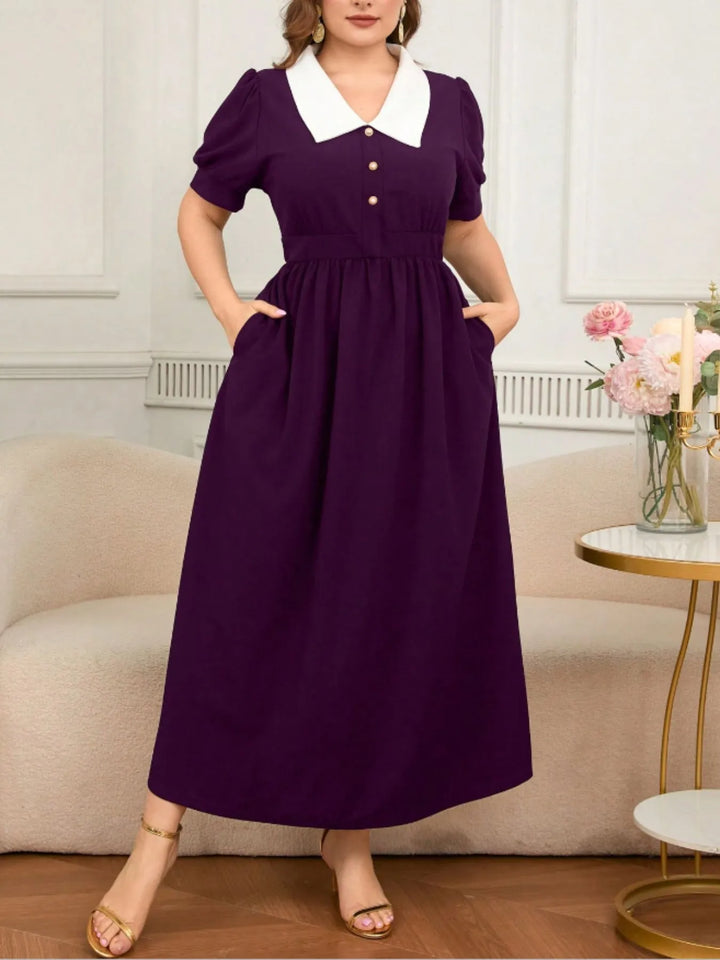 Person wearing a purple dress in an indoor setting with a couch and flowers.