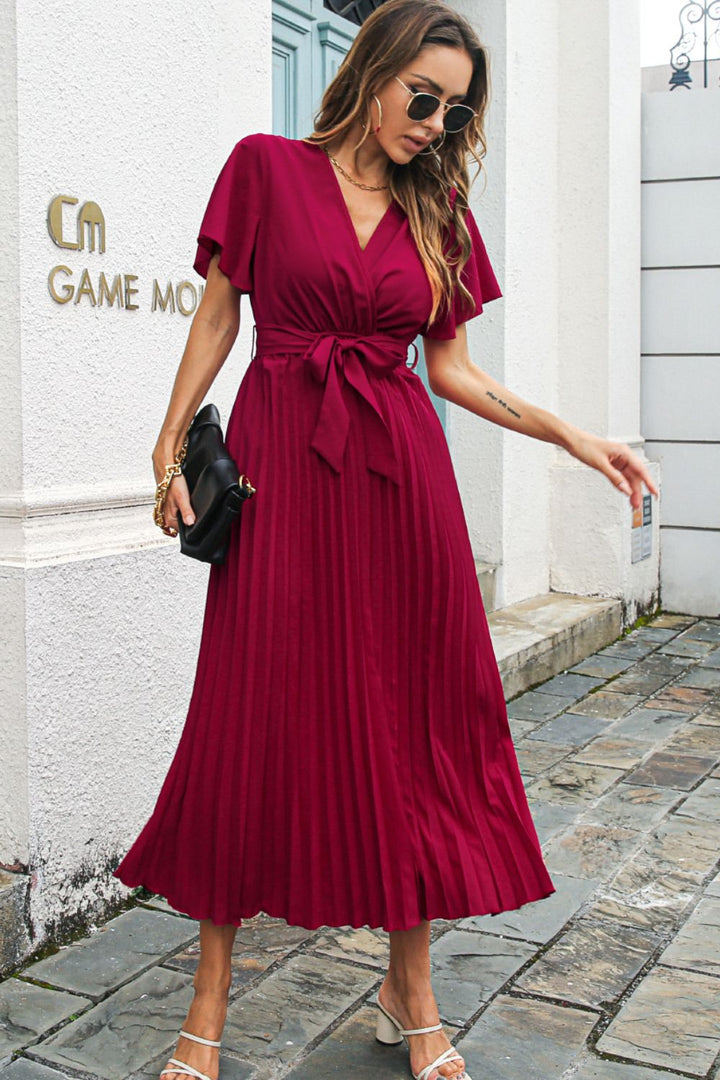 Woman in a red midi dress walking on a street.