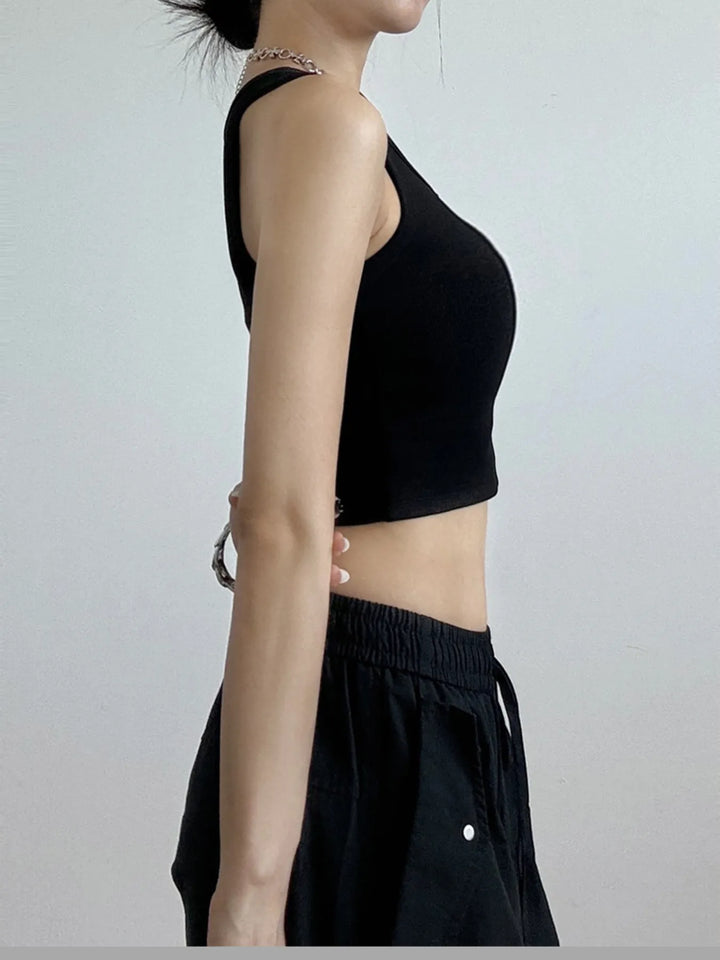 Person wearing a black sleeveless cropped top and black pants on a plain background