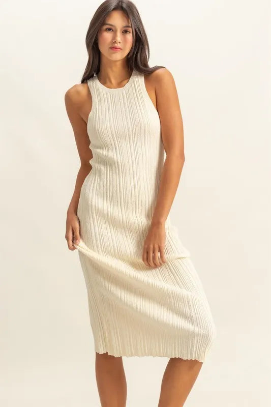Woman wearing a white ribbed midi dress against a plain background