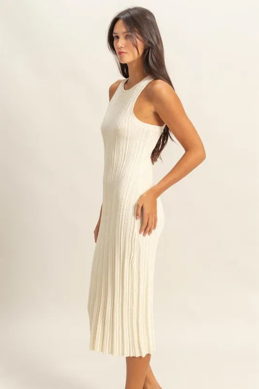 Woman wearing a white pleated midi dress against a plain background