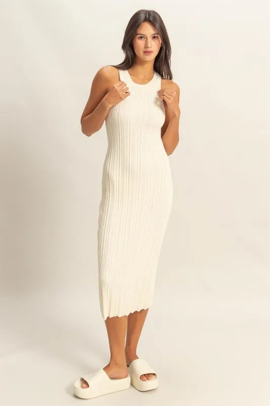 Woman wearing a white sleeveless  midi dress against a plain background