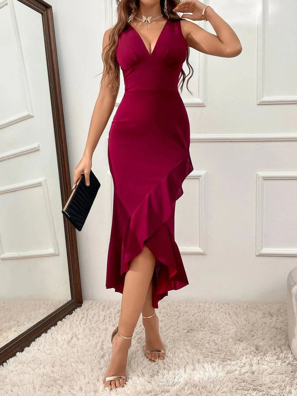 Woman wearing a burgundy midi dress with a white wall background