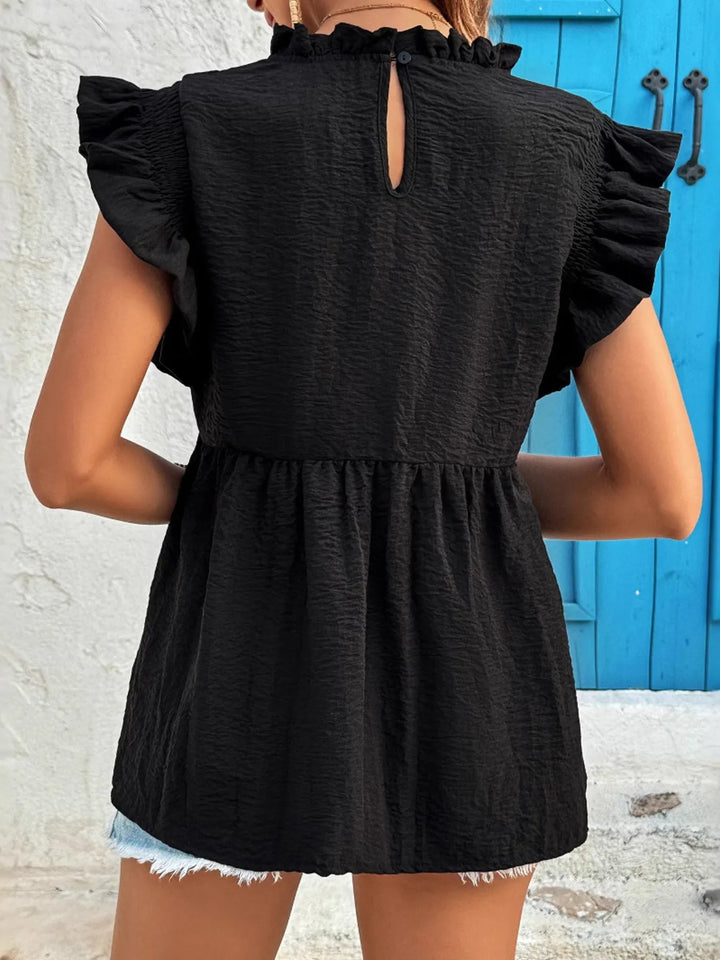 Black sleeveless blouse worn by a person with a blue door in the background
