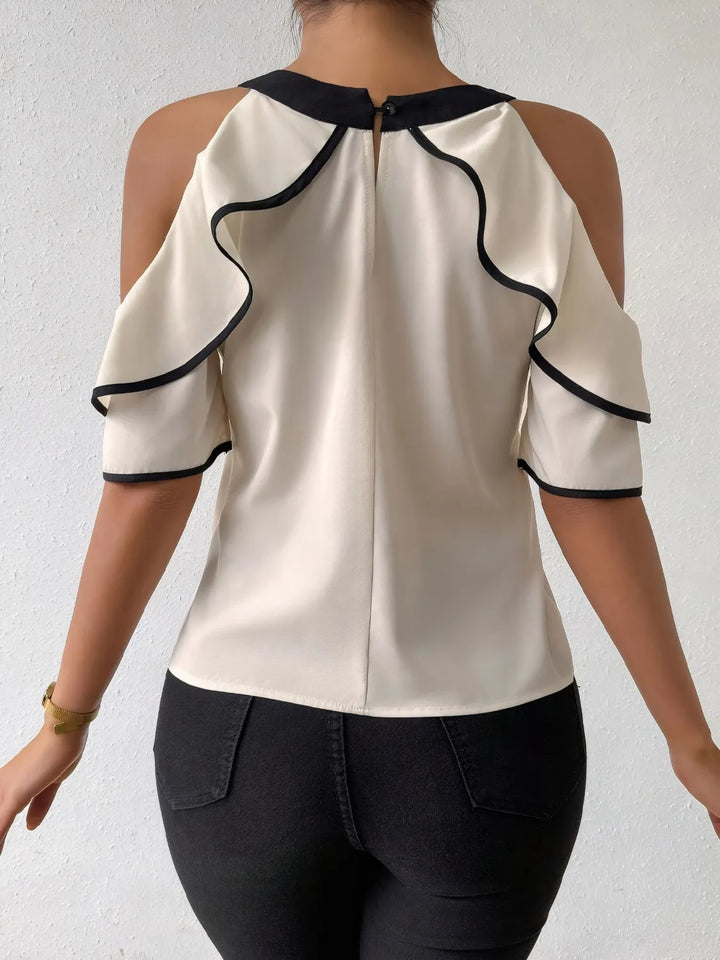 White blouse with black trim on a plain background