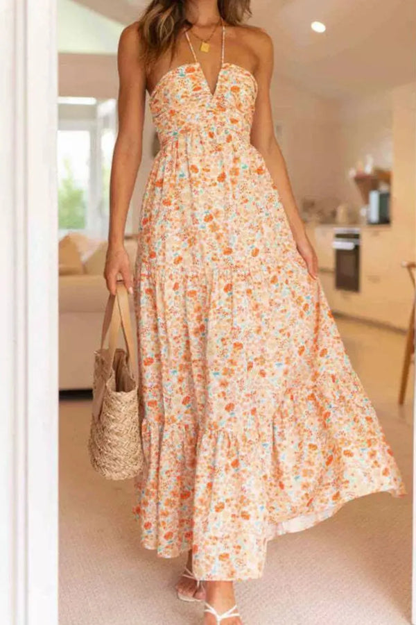 Woman wearing a sherbet floral maxi dress holding a straw bag in a kitchen setting