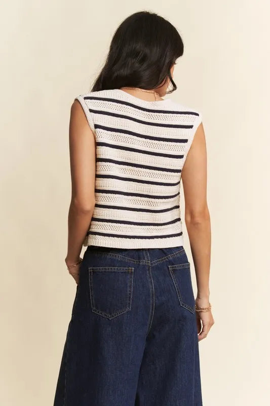 Person wearing a sleeveless striped top and blue jeans on a beige background