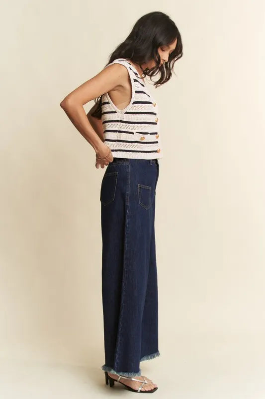 Woman wearing a striped tank top and dark blue jeans against a beige background
