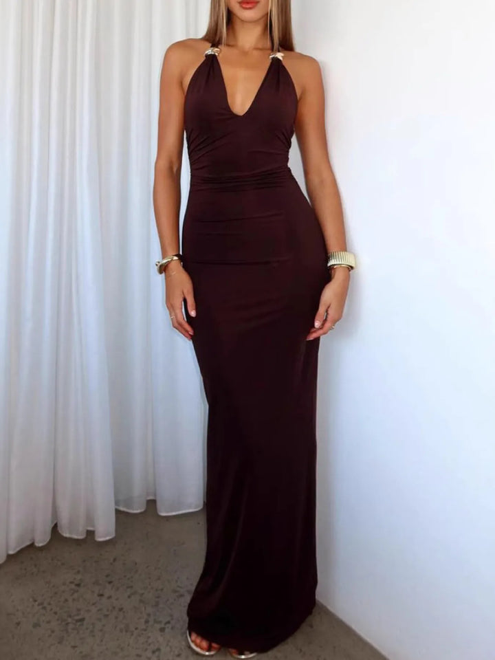 Woman wearing a wine red halter neck dress against a white curtain background