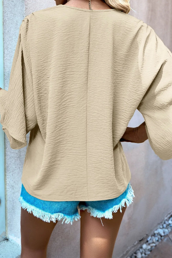 Person wearing a beige top and blue shorts with a neutral background