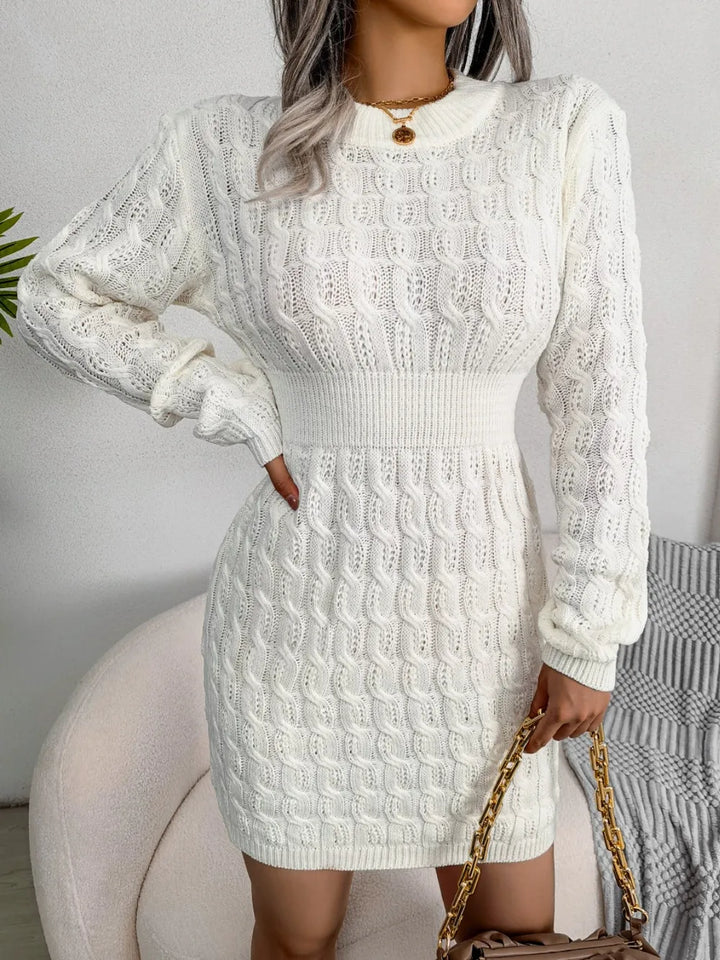 Person wearing a white cable knit dress with long sleeves against a neutral background