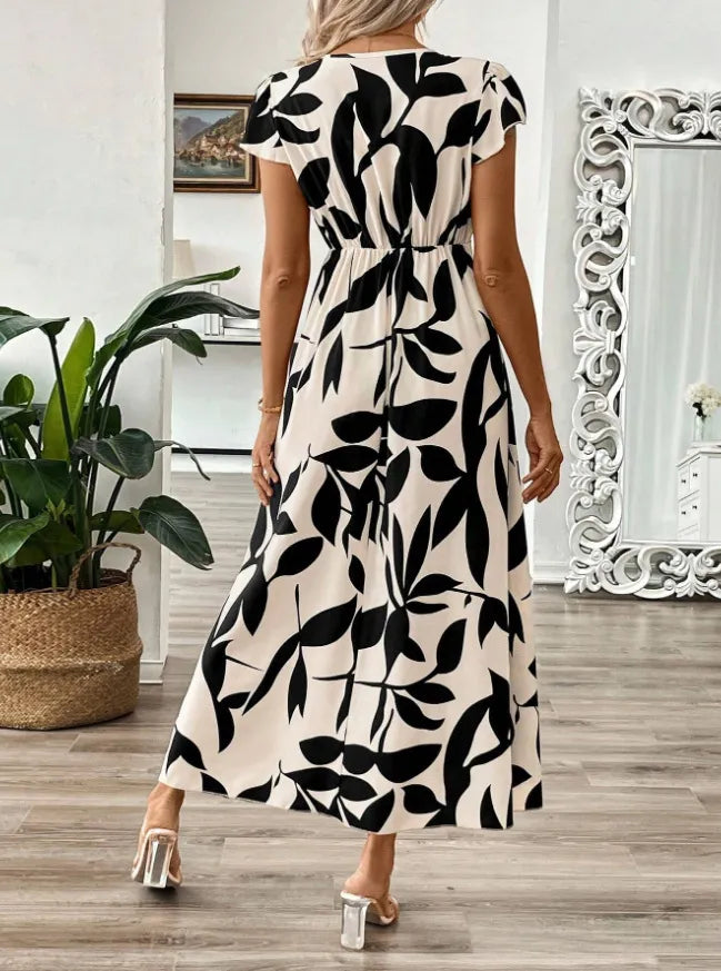 Woman wearing a black and white patterned dress in a room with decor elements.
