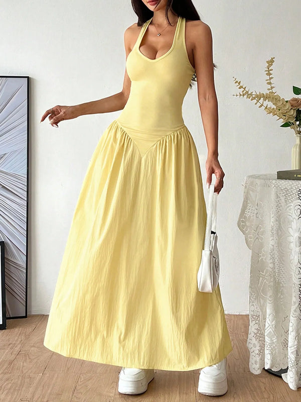 Woman wearing a yellow Halter Neck Maxi Dress standing in a room with a white wall and decorative elements.