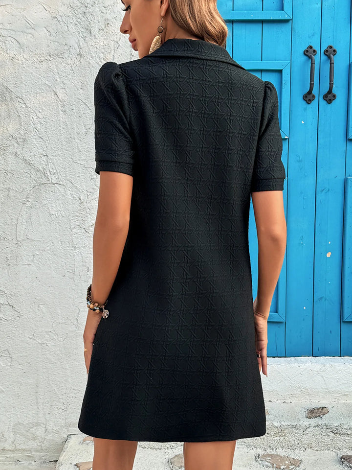 Woman wearing a black casual mini dress standing in front of a blue door.
