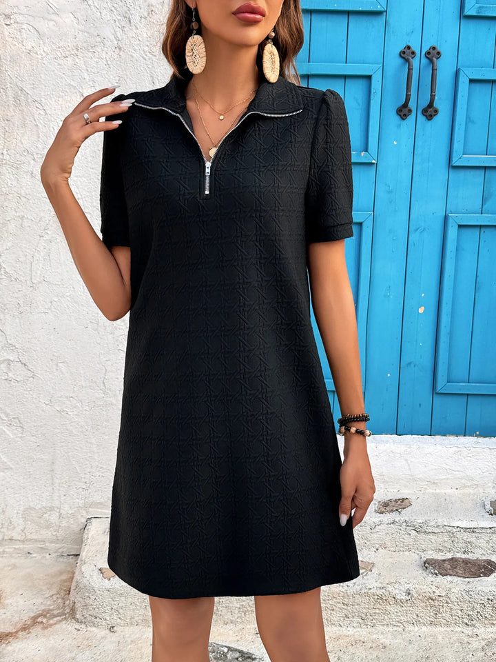 Woman wearing a black mini casual dress with a blue door in the background